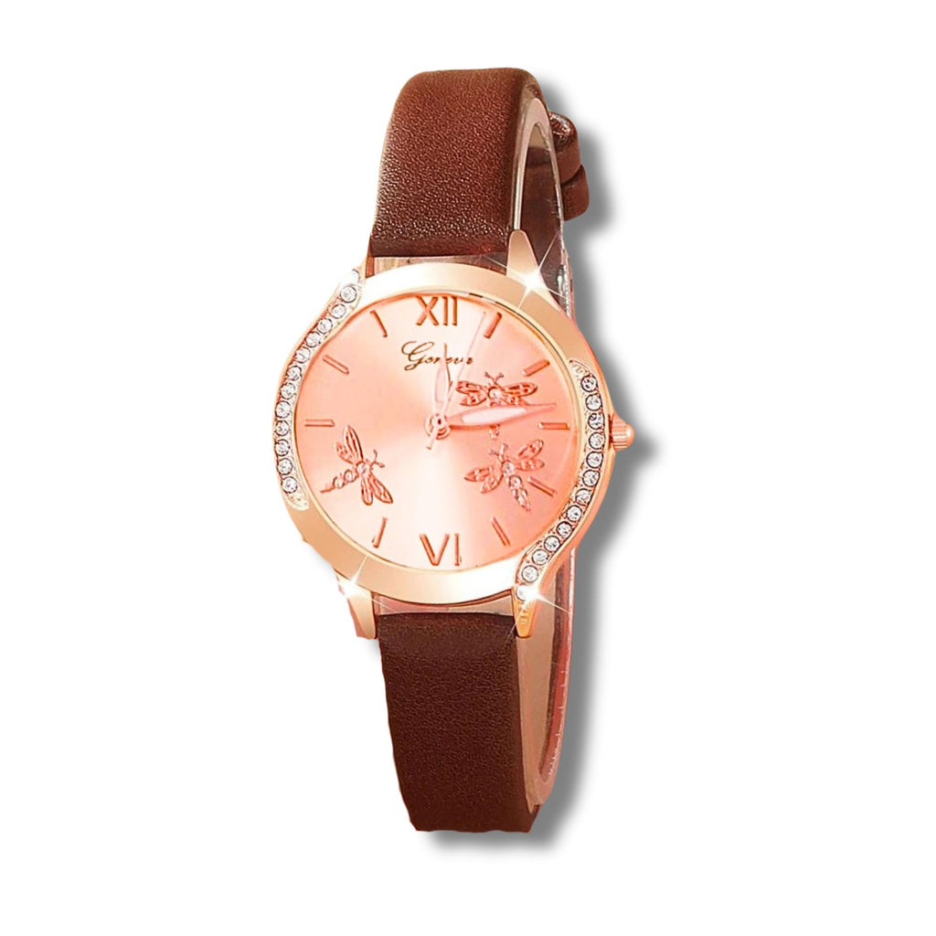 rose gold face watch with 3 dragonflies on it with roman numeral number 12 and 6. with a rose gold trim with  crystals on either side and an elegant brown strap on a white background