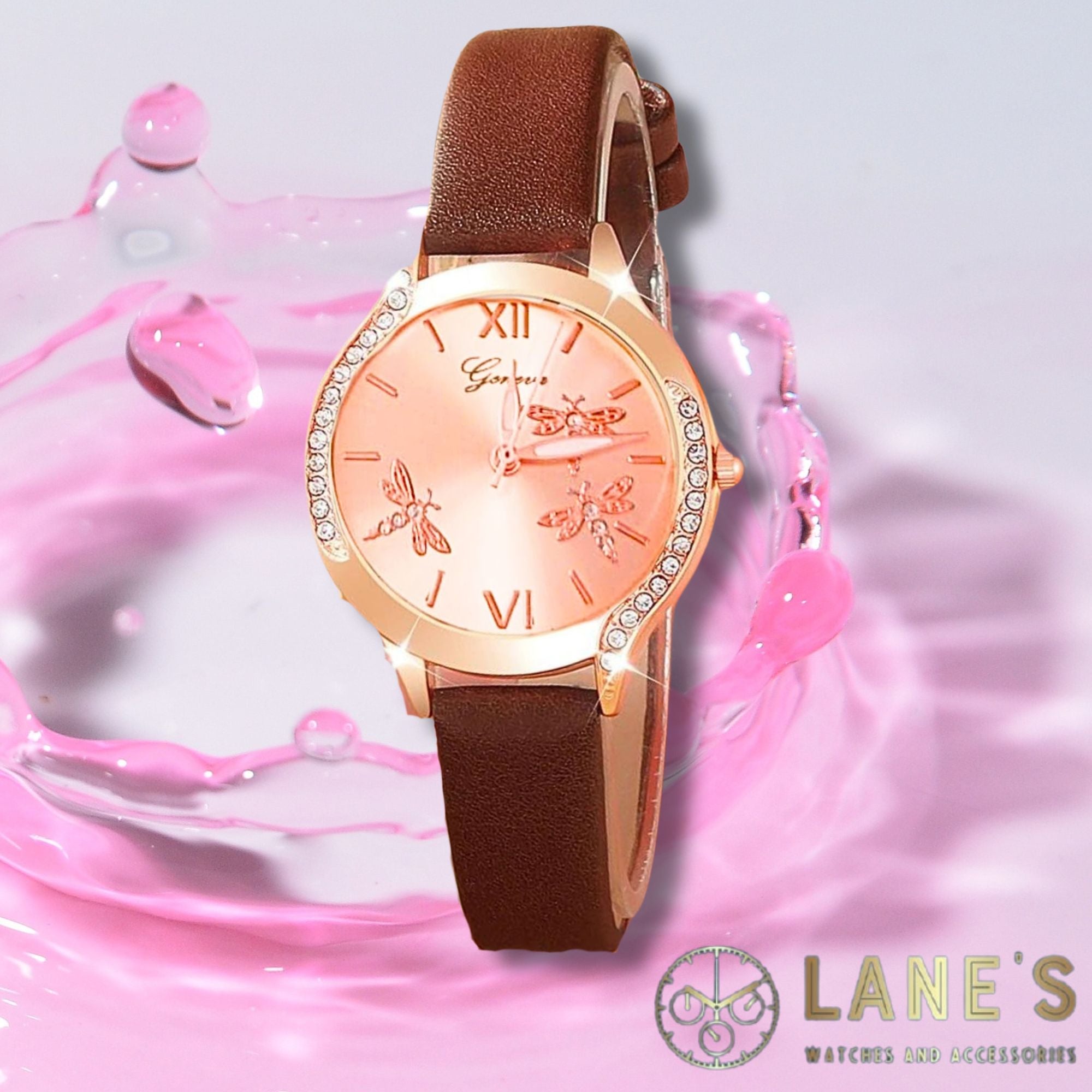 rose gold face watch with 3 dragonflies on it with roman numeral number 12 and 6. with a rose gold trim with  crystals on either side and an elegant brown strap on a pink background