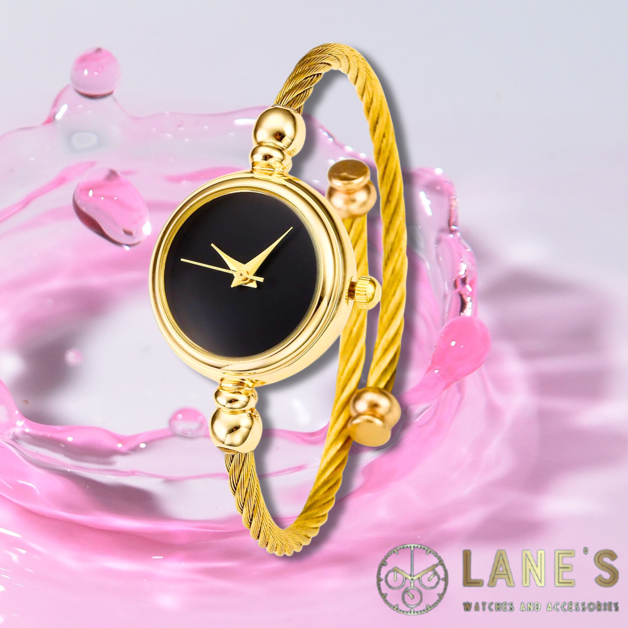 gold circle watch with a black face with no numbers or lines with a gold trim and a thin gold rope strap on a pink background