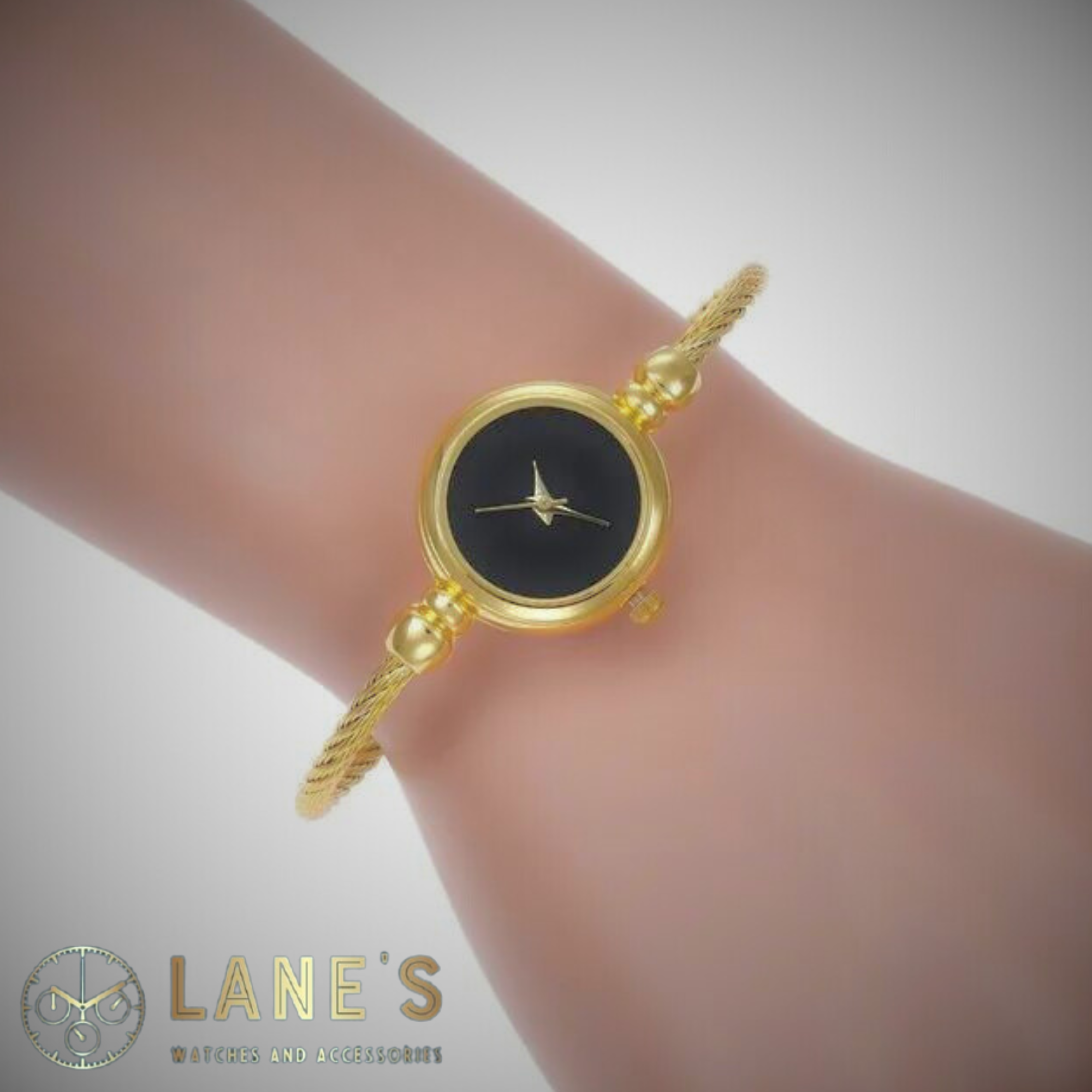 gold circle watch with a black face with no numbers or lines with a gold trim and a thin gold rope strap on a woman's wrist