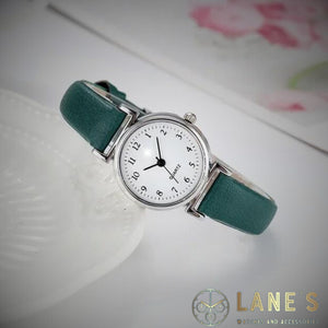 Green Meadow Ladies watch. Green strap, white face with silver trim. Numbers in black 1-12 with hour minute and second hands