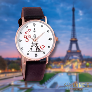 white faced watch with a mini Eiffel tower and 5 red floating hearts with pin points representing numbers with a gold trim and a black strap on a Paris Eiffel tower background