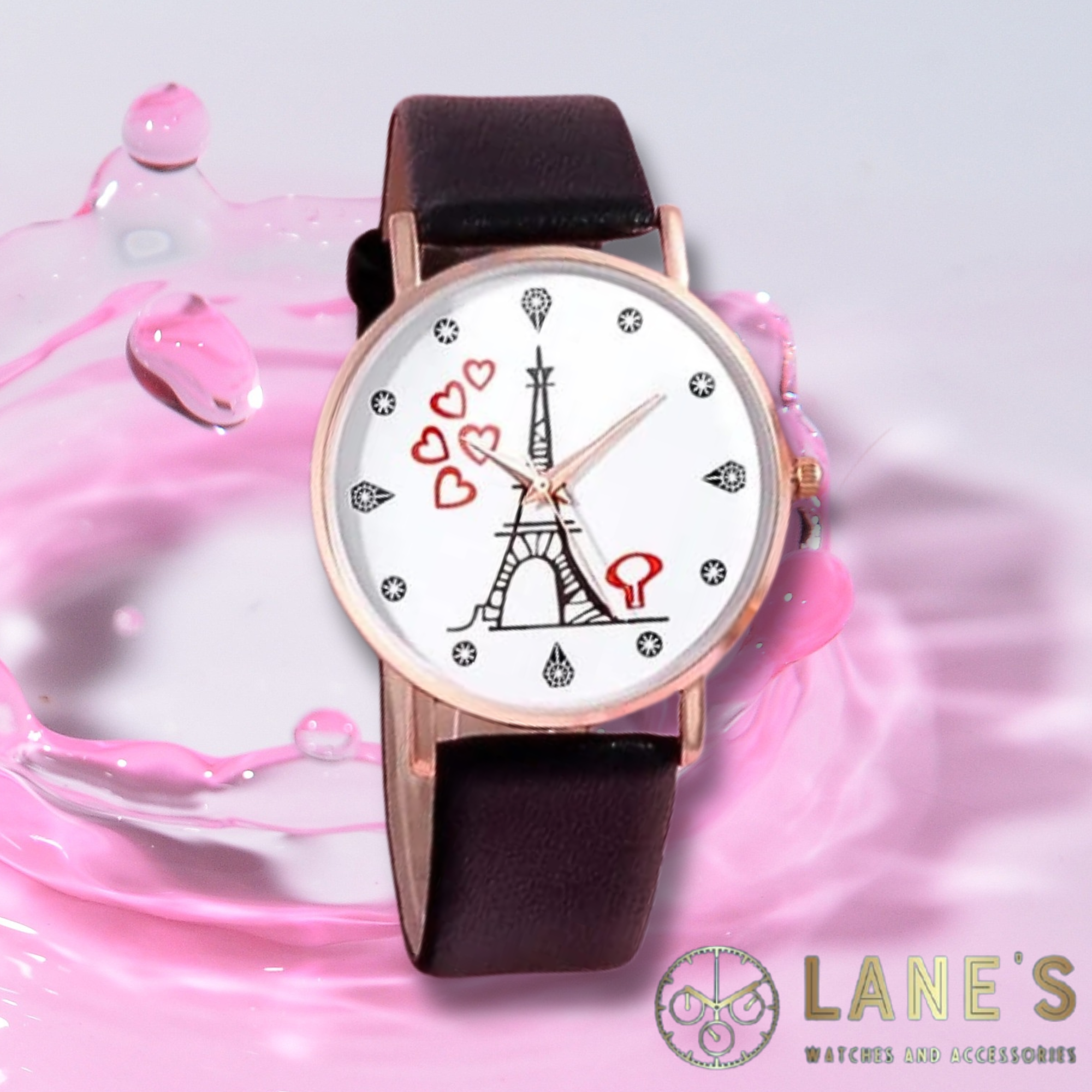 white faced watch with a mini Eiffel tower and 5 red floating hearts with pin points representing numbers with a gold trim and a black strap on a pink background