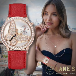 crystal butterfly with a light gold back ground with a small clock with only the number 3 6 9 and 12 on it. the butterfly is big and the clock is in the right top corner. with a crystal trim and a red strap  on a woman's wrist