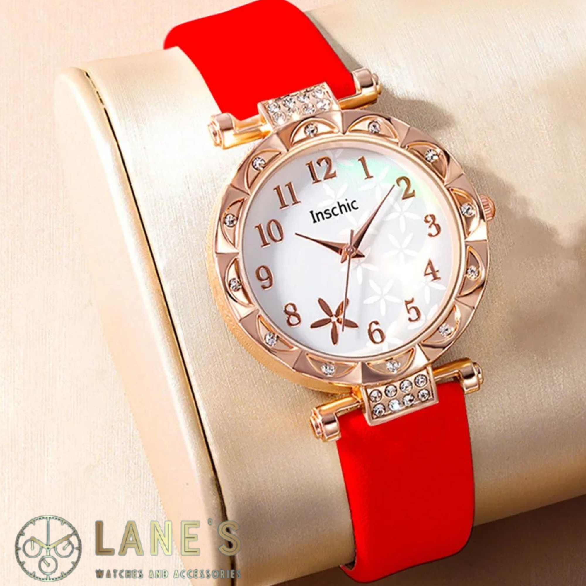 white faced watch with gold numbers and a gold trim with crystals and a red strap