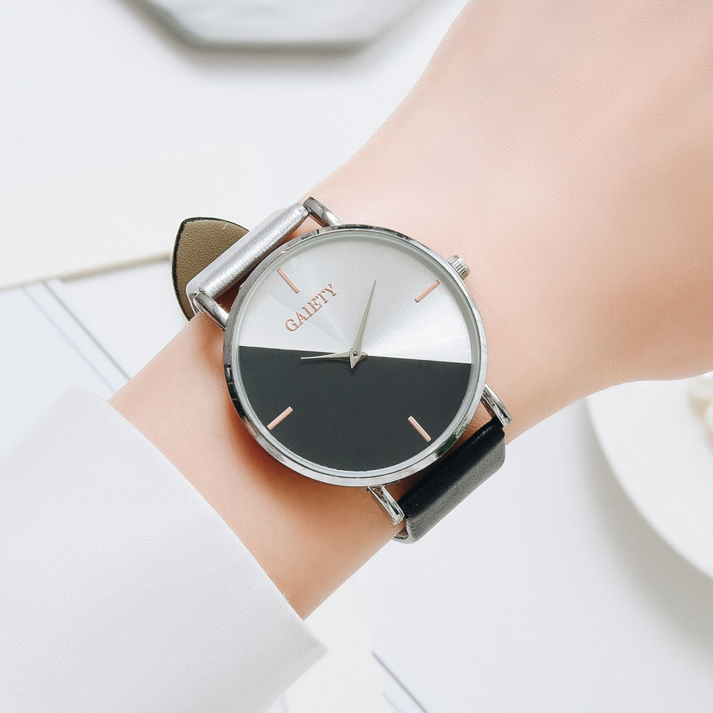 half black and half silver faced watch with 4 rose gold lines representing numbers with a silver trim and one black strap and one silver strap on a woman's wrist