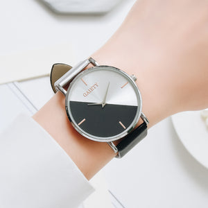 half black and half silver faced watch with 4 rose gold lines representing numbers with a silver trim and one black strap and one silver strap on a woman's wrist