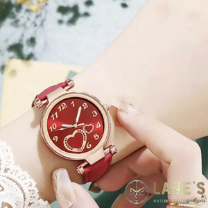 red faced watch with two gold hearts and gold numbers with a gold trim and a red faux leather strap on a woman's wrist